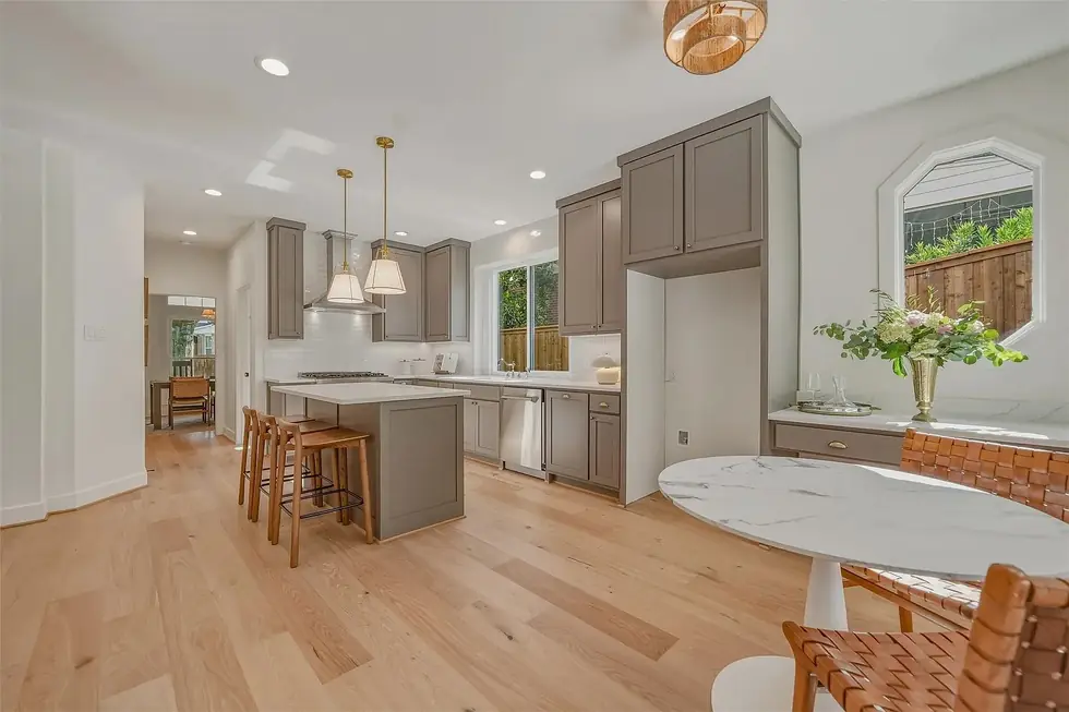 A rebuilt open kitchen with grey cabinets, an island with stools and an oak floor